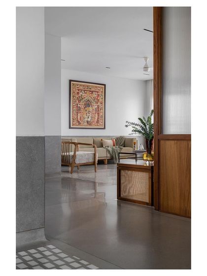 The transition from the polished concrete hallway to the tiled living area, framed by a wooden doorway.
