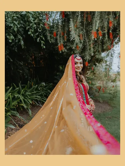 A beautiful shot of the bride, her colorful veil flowing, captured in a garden setting.