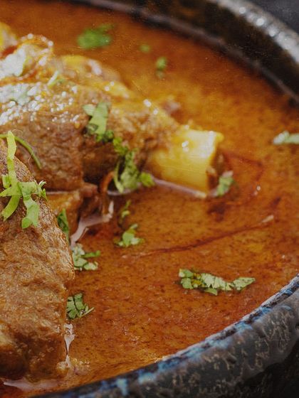 Another look at our slow-cooked mutton curry, a highlight of our North Indian fare. The deep color of the gravy and the fresh cilantro garnish promise a dish that is both visually appealing and packed with traditional spices.
