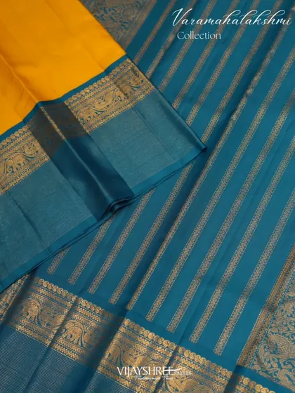 A vibrant yellow and blue contrast Kanjivaram featuring delicate Oosi zari lines, a fine needle-like weaving technique that adds a subtle shimmer. The border is adorned with traditional elephant motifs.