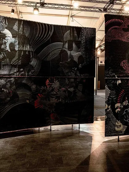 A wide shot of the 'Gothilicious' installation. The large, curved panels of woven black fabric create an immersive environment that explores the moody and sensual aspects of contemporary Goth culture.