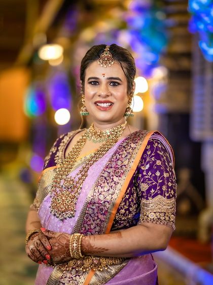 A client at her son's naming ceremony, looking regal in a lavender Kanjeevaram saree and a custom-designed, heavily embroidered purple blouse.