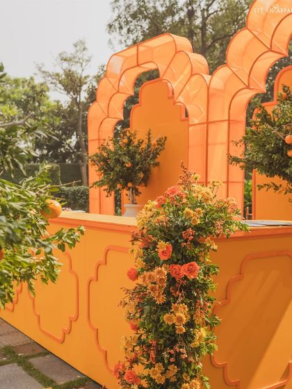 The vibrant orange bar is adorned with fresh flowers and orange trees, making it a stunning focal point.