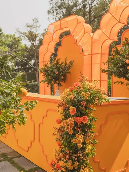 The vibrant orange bar is adorned with fresh flowers and orange trees, making it a stunning focal point.