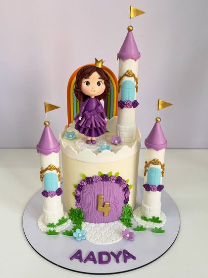 Another view of the princess castle cake, personalized with the birthday girl's name, "Aadya," at the base, completing this royal fourth birthday celebration centerpiece.