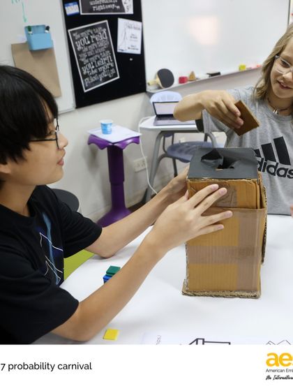 Two seventh-grade students explain their probability game to a classmate. This project required them to design, build, and host a carnival, applying their math skills in a creative and collaborative way.