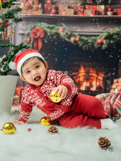 A fun action shot of the toddler playing on the fluffy white rug, surrounded by Christmas decorations.