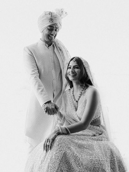 A joyful black and white portrait. The groom's laughter is infectious as he holds his bride's hand. This image captures the fun and happiness that is so central to a wedding celebration.