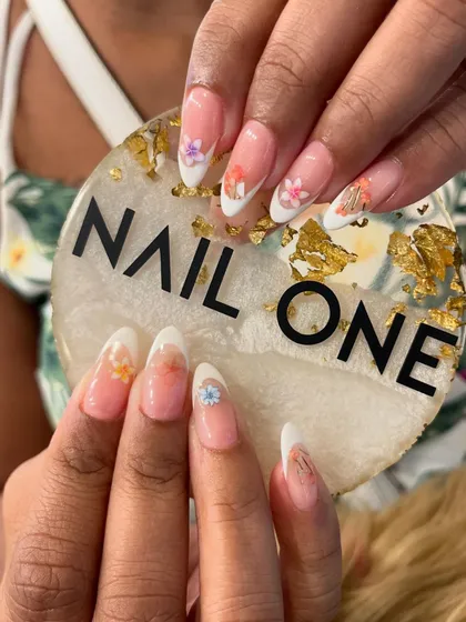 A fresh and delicate take on the French manicure. This design features a classic white tip on an almond-shaped nail, enhanced with tiny, hand-painted flowers in soft pastel colors for a subtle, summery feel.