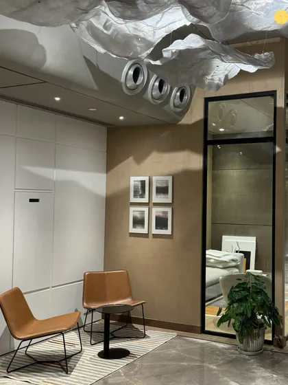A quiet seating nook in 'Project LH.' This corner provides a space for informal meetings or a moment of pause, featuring comfortable leather chairs and a custom light installation that adds an artistic touch to the corporate environment.