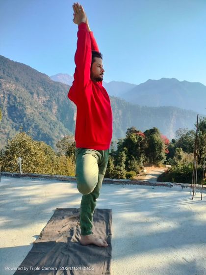 Holding Vrikshasana, or Tree Pose, on a rooftop in the mountains. This balancing asana improves focus and concentration while strengthening the legs and core.