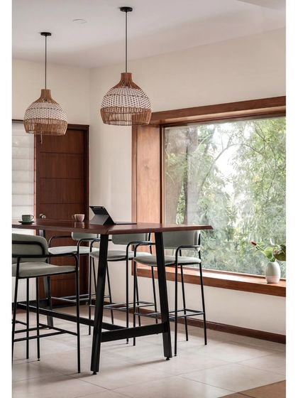 A closer look at the community table on the upper floor of Kana Cafe. The rattan pendant lights and large window create a bright and inspiring space for work or conversation.