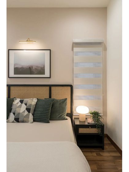 A bedroom that combines classic and contemporary elements, with a cane headboard, modern bedside lamp, and a neutral color palette.