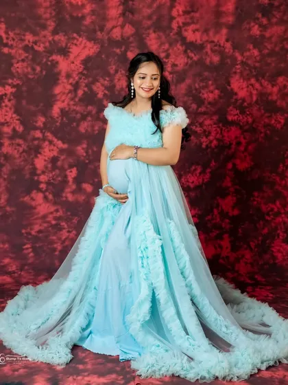 This stunning light blue ruffled gown features a long, dramatic train. It's a perfect choice for a fairytale-themed maternity or pre-wedding shoot.