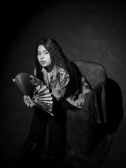 The same artistic portrait, this time in black and white. This version emphasizes the textures of the crimped hair and the fabrics, creating a timeless and dramatic feel.