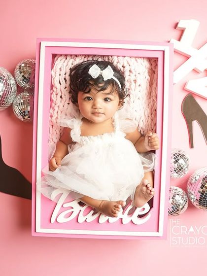 A creative half-birthday shoot with a "baby in a box" Barbie theme. This little girl is a perfect doll, surrounded by disco balls and high heels props.