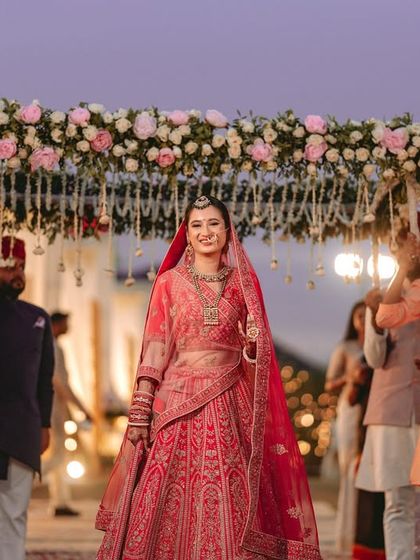 The bride's grand entrance under a 'phoolon ki chadar' (floral canopy), a timeless and emotional moment.
