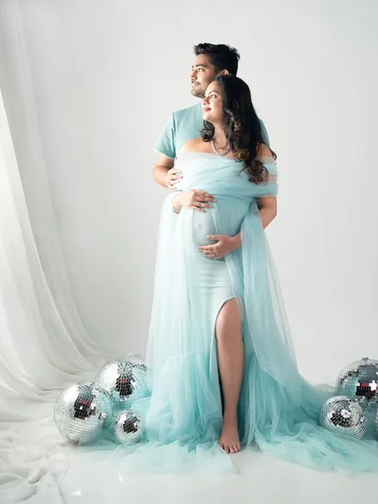 Looking towards the future together. This portrait, with its dreamy light blue gown and disco ball props, adds a touch of modern glamour to your maternity photoshoot.