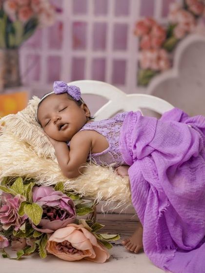 A purple dream. This elaborate setup with a miniature bed, flowers, and soft fabrics creates a truly magical and royal portrait.