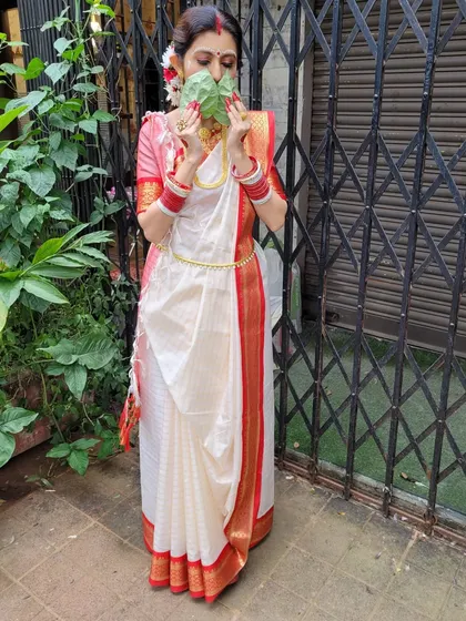 This image captures a traditional moment during Durga Puja celebrations. The drape is neat and secure, allowing for easy movement while maintaining its elegant form.