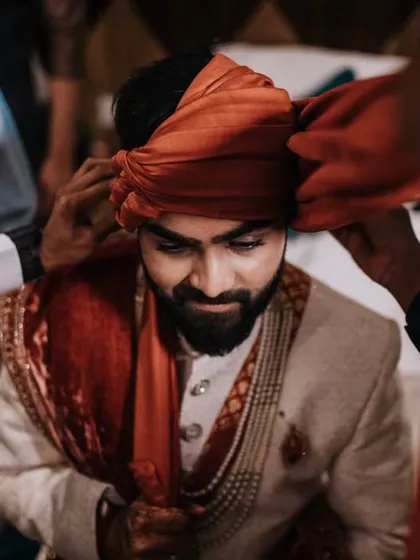 A candid moment of the groom's turban being tied. This is a significant part of the getting-ready ritual, full of tradition.