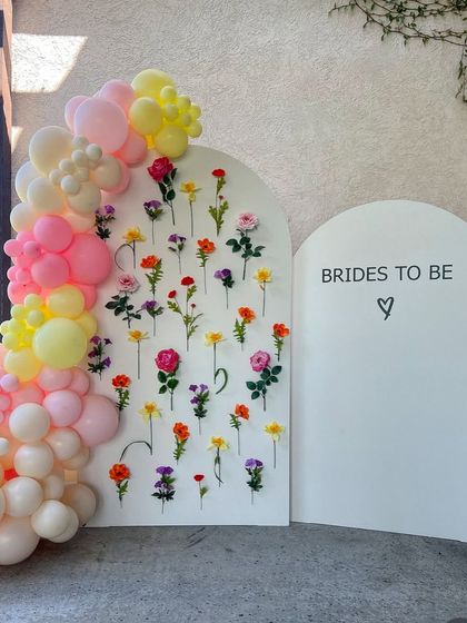 A playful and colorful take on the flower wall backdrop, combined with a pastel balloon garland for a fun and festive bridal shower.