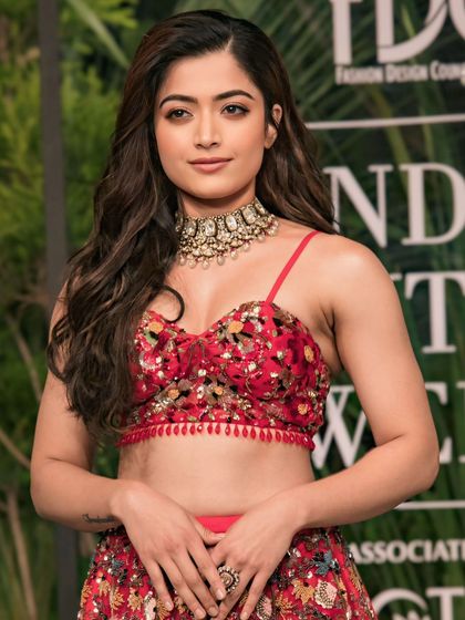 A close-up of Rashmika Mandanna, showcasing her flawless beauty and the intricate choker necklace that complements her red lehenga.