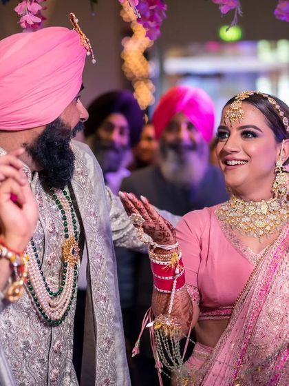 A candid, happy moment between a Sikh couple during their wedding celebrations, full of life and color.