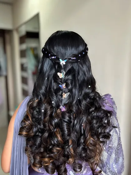 A closer look at this enchanting butterfly hairstyle. The combination of curls, a fishtail braid, and colorful butterfly clips is perfect for a mehendi or sangeet.