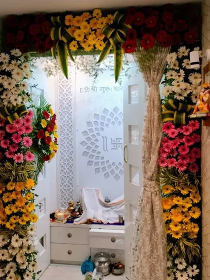 A full floral entrance for a home mandir. We used a rainbow of gerbera daisies and other colorful flowers to create a grand and welcoming archway leading into the serene, white prayer room.