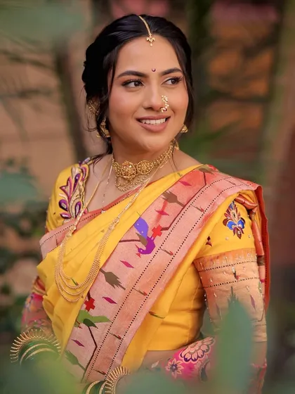 A side profile of Anchita, showing the soft braided hairstyle and the beautiful details of her Paithani nauvari blouse.