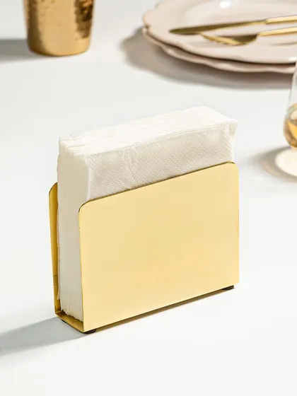 A minimalist shot of a modern, solid gold napkin holder. The styling uses clean lines and a simple background to emphasize the product's sleek design.