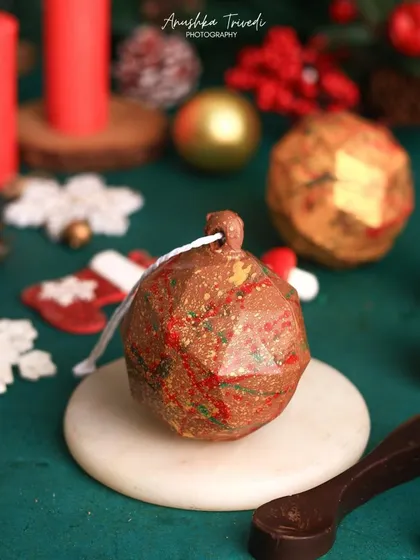 A unique, breakable chocolate ornament for Christmas. This shot captures the novelty and fun of the product, making it an exciting and intriguing holiday treat.
