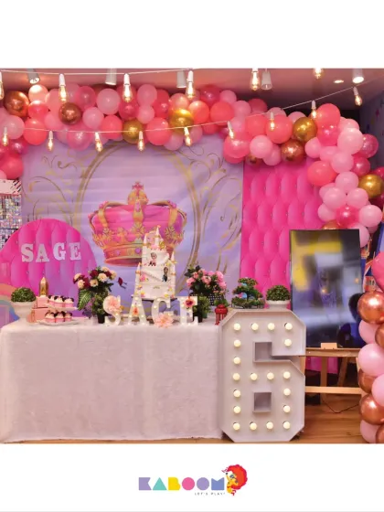 A royal celebration fit for a princess, this theme features a pink castle backdrop, a large crown detail, and sparkling gold and rose-gold balloons for a glamorous sixth birthday.