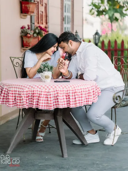 An intimate moment shared over a table at a charming cafe. This photo captures the sweet, romantic side of a couple's relationship in a relaxed and picturesque setting.