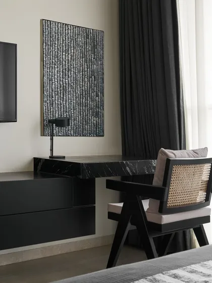 This study nook in the Slate Bedroom features a custom cantilevered desk made from matte black Marquina marble. Paired with a classic cane-backed chair, this workspace is a perfect blend of luxurious materials and timeless design.