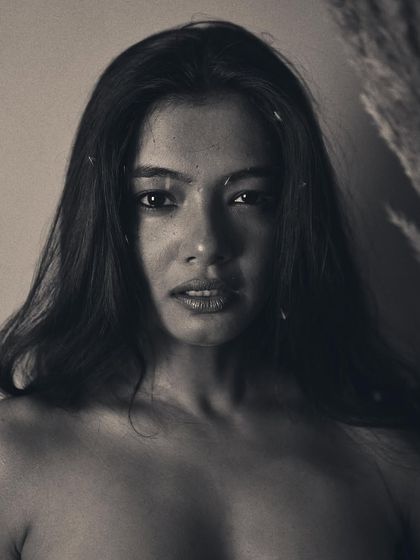 A direct and powerful gaze is the focus of this black and white portrait. The soft, grainy texture adds a timeless feel, while the simple composition keeps all the attention on the model's expressive face.