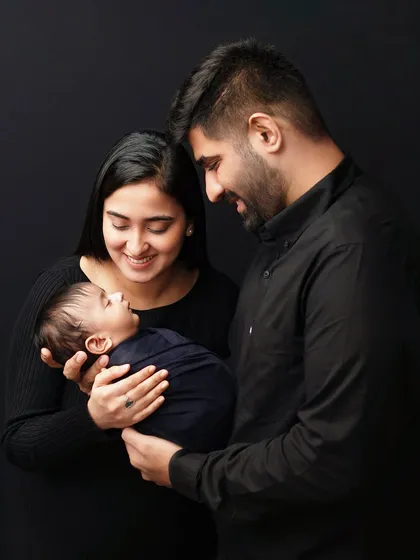 New parents gazing lovingly at their baby. I guide families into poses that feel natural and highlight their connection, creating authentic family portraits.