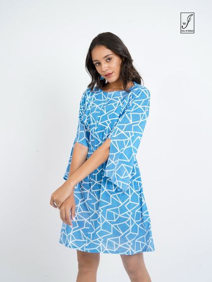 A model in a blue patterned dress, shot against a clean white background for a brand's online store.