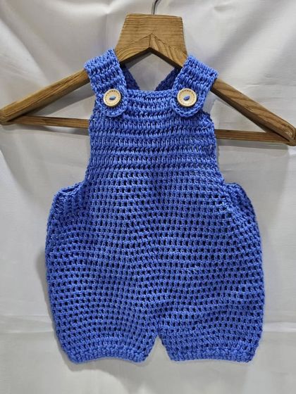 This handmade crochet baby romper is perfect for keeping your little one comfortable and stylish. It's made from soft cotton with wooden button details on the straps.