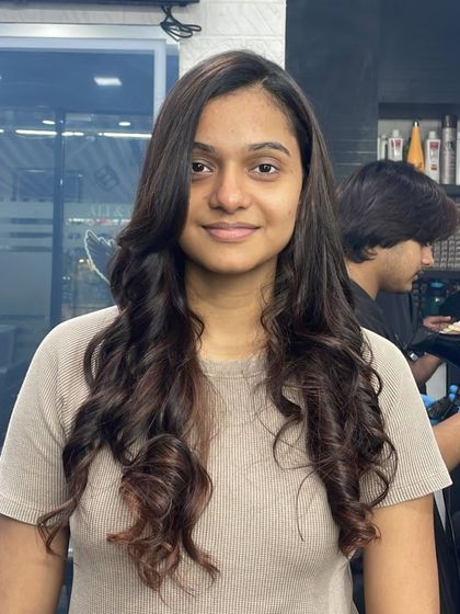 This client's long hair is styled into beautiful, defined curls, showing off her healthy and voluminous locks.