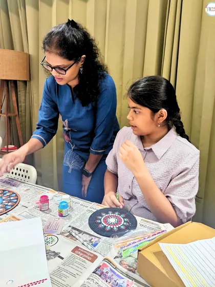 An instructor offers guidance on technique during our dot mandala workshop, helping a student perfect her design.