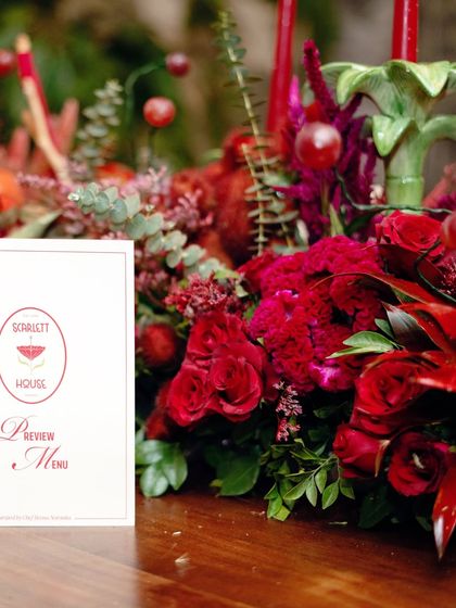 The custom menu for the "Scarlet House" preview, elegantly placed next to a dense arrangement of red roses and cockscomb flowers. Every detail is designed to be cohesive and luxurious.