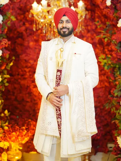 The groom deserves his own moment in the spotlight. This portrait captures the pride and elegance of the groom in his wedding sherwani, standing against a rich floral backdrop.