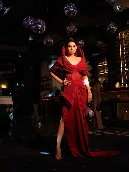 Another look at the crimson slit gown, where the structured hood and flowing train create a silhouette of pure confidence.