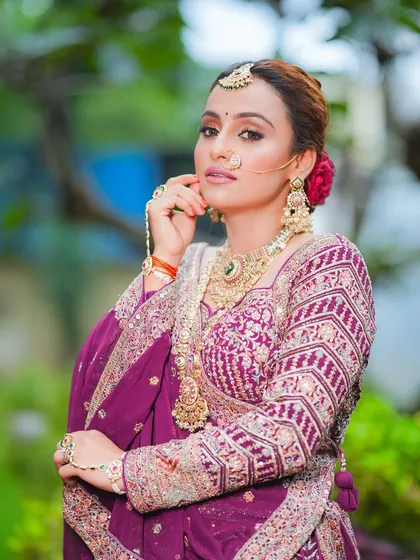 Channeling her inner queen with this majestic bridal look. The focus is on her powerful gaze, enhanced with subtle eyeshadow and a full brow, paired with heavy traditional jewelry.