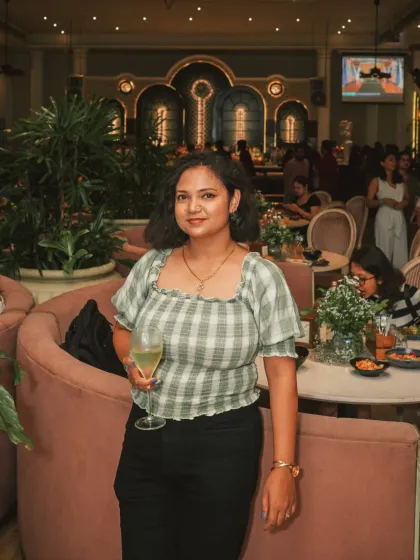 A guest enjoying a glass of wine during a corporate event. The soft pink booths and ambient lighting create a relaxed atmosphere, a world away from a typical conference room.