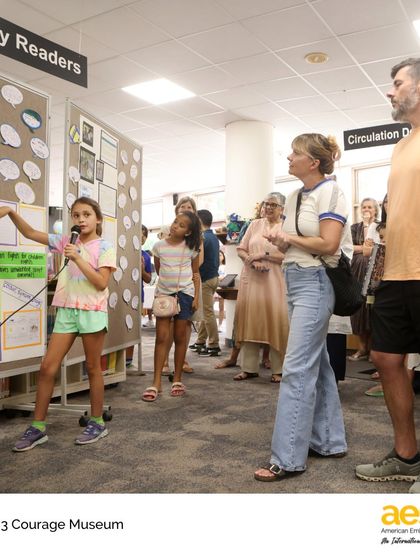 Our Grade 3 Courage Museum in action. A student presents her exhibit, sharing stories of courageous individuals she researched. This project integrates reading, writing, and social studies, empowering students to find and share their voices.