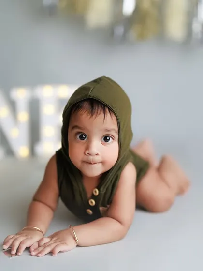 How adorable is this little one during his first birthday milestone session? The "ONE" marquee lights add a celebratory touch to this classic studio portrait.
