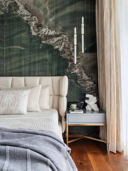 A closer look at the master bedroom's headboard wall, where fluted green marble creates a stunning textural and visual anchor. The wingback-style upholstered headboard and minimalist bedside lighting complete this picture of modern luxury.